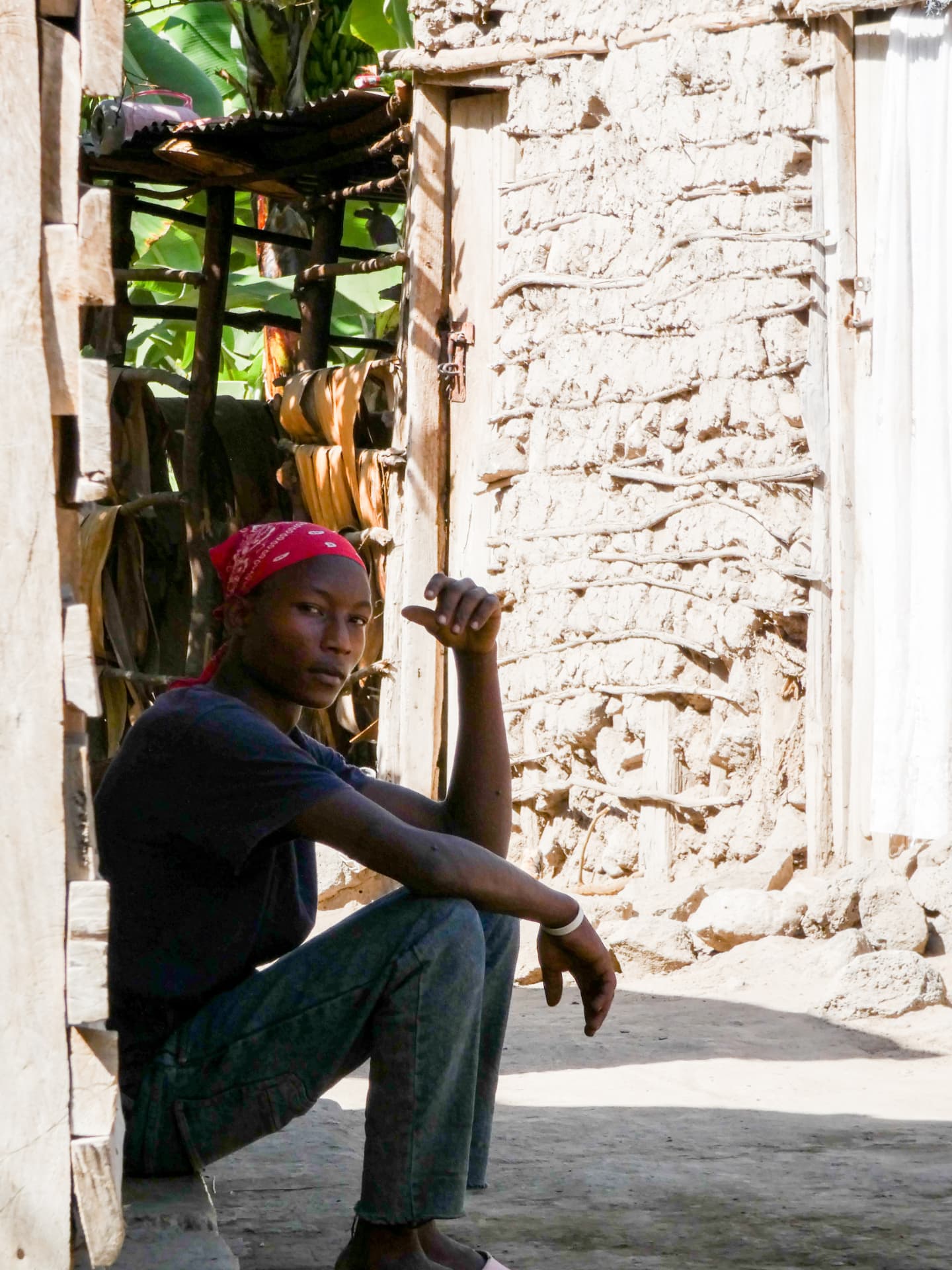 Young man sitting in the doorway of a traditional house near Lake Manyara
