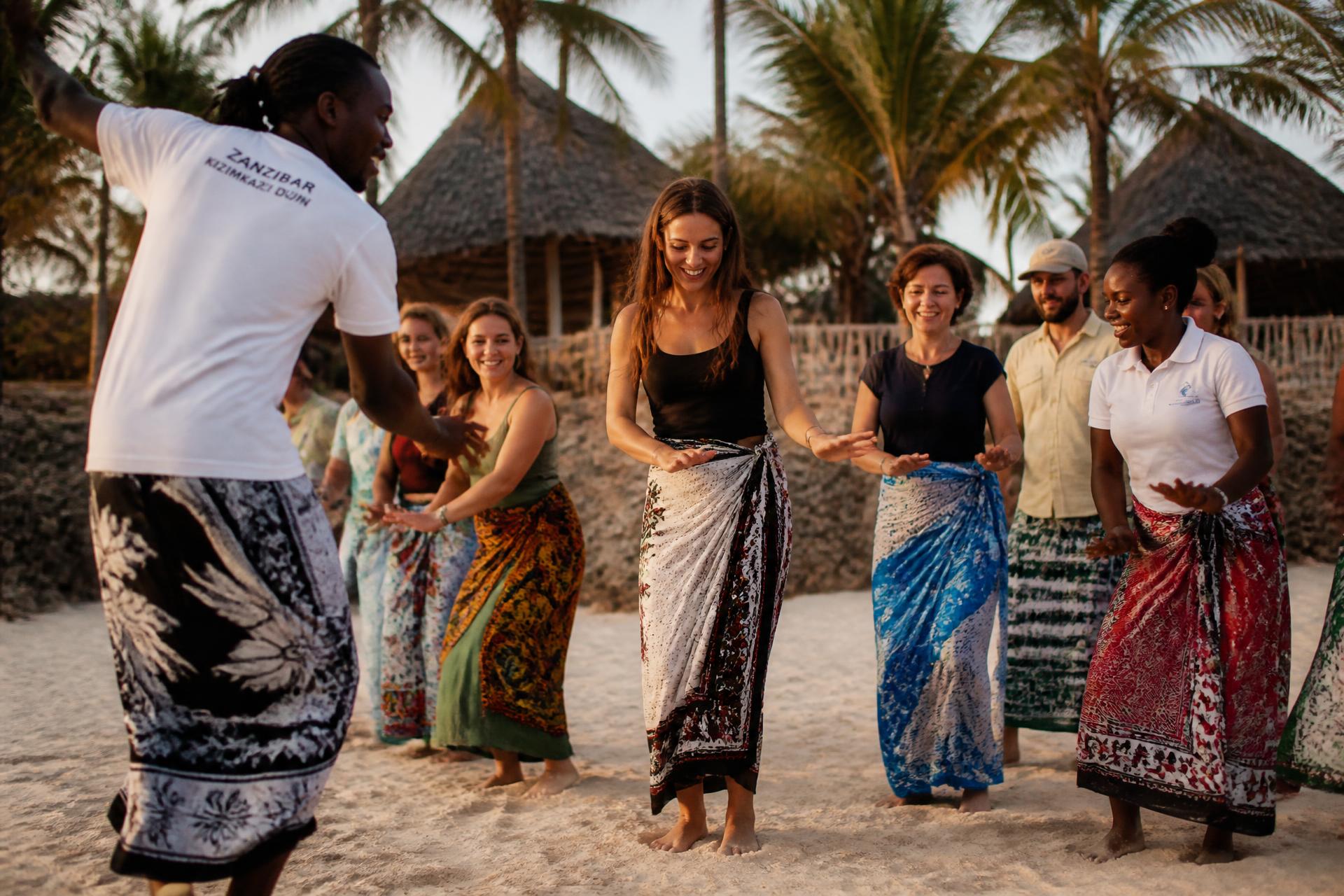 Travellers learning traditional Swahili dance on a Zanzibar beach